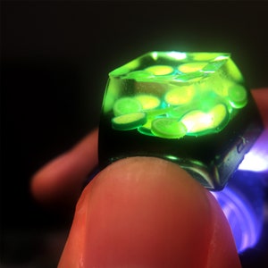 May include: A green resin keycap with a clear top filled with lime slices. The keycap is illuminated from below, making the lime slices glow.