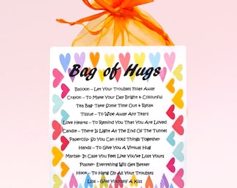 May include: A white card with colorful hearts printed around the edges. The card has the text "Bag of Hugs" printed in black at the top. Below the title, there is a list of items with descriptions, such as "Balloon - Let Your Troubles Float Away" and "Crayon - To Make Your Day Bright & Colourful".