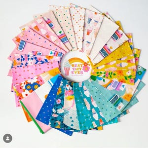 Peut inclure: Un assortiment de tissus colorés disposés en cercle. Les motifs comprennent des cônes de crème glacée, des machines à écrire et des motifs floraux. Un bouton central affiche le texte "Best Day Ever" avec un arc-en-ciel et une glace.