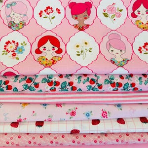 Peut inclure: Une pile de tissus roses avec divers motifs. La couche supérieure présente des images répétées de filles et de fleurs dans des cadres blancs. D'autres couches incluent des motifs de fraises, floraux et rayés. Idéal pour le patchwork et l'artisanat.
