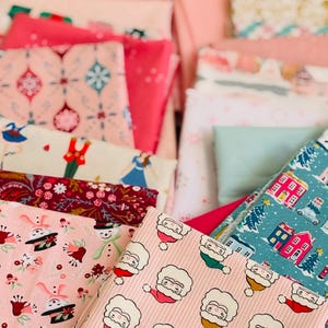 Könnte beinhalten: Eine Sammlung von rosa und roten Stoffstücken mit verschiedenen Mustern. Designs umfassen Weihnachtsmann-Gesichter, Blumenarrangements und Urlaubsszenen. Die Stoffe sind gestapelt und zeigen eine Vielzahl von Texturen und Drucken, ideal für Bastel- und Nähprojekte.