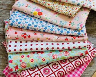 Peut inclure: Une pile de tissus pliés présentant divers motifs, notamment de petites fleurs, des fraises, des formes géométriques rouges et blanches et un motif vichy rose vif. Les textiles affichent une gamme de couleurs comme le rouge, le bleu, le rose et le blanc.