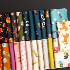 May include: Folded fabric pieces with diverse, colourful patterns. Designs include apples, flowers, moons, stars, rainbows, and houses. The fabrics are in shades of black, green, blue, orange, pink, and yellow. Some fabrics have a white background.