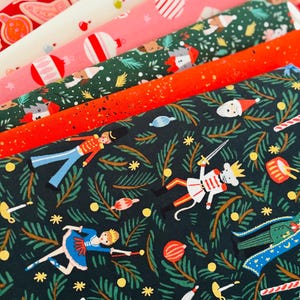 Può includere: Una collezione di rotoli di tessuto piegati con motivi natalizi. I disegni includono figure di schiaccianoci, ballerini, topi con spade, decorazioni natalizie, bastoncini di zucchero e rami di pino nei toni del rosso, verde e bianco.