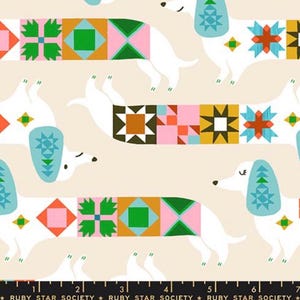 Può includere: Tessuto con un motivo ripetitivo di bassotti bianchi su sfondo crema. I cani hanno orecchie azzurre e corpi decorati con blocchi geometrici colorati in stile patchwork nelle tonalità rosa, verde, arancione e marrone. Include un righello.