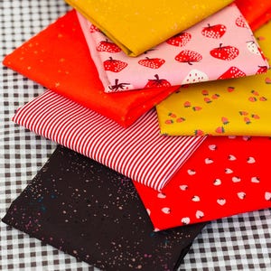 Peut inclure: Un assortiment de carrés de tissu pliés de différentes couleurs et motifs. Comprend du rouge à rayures blanches, du rouge avec des fraises blanches et du jaune avec de petites fraises. D'autres tissus sont rouge uni, jaune et noir avec des mouchetures blanches.