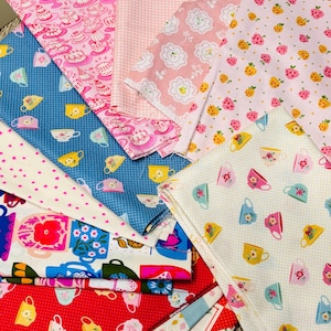 Puede incluir: Una colección de muestras de tela coloridas con varios patrones. Los diseños incluyen pasteles rosas, fresas, tazas de té y motivos florales. Los colores incluyen rosa, azul, rojo y blanco. Las telas son probablemente de algodón o un material similar.