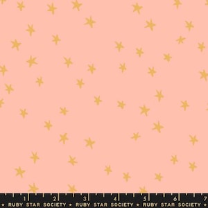 May include: A fabric featuring a repeating pattern of gold stars on a light coral background. The stars are hand-drawn in a simple, whimsical style. Suitable for quilting, clothing, or home decor projects. The fabric is from Ruby Star Society.