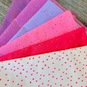 Peut inclure: Échantillons de tissus colorés dans les tons de rose, violet et blanc. Certains tissus ont un motif tacheté, d'autres présentent des étoiles roses vives. Idéal pour les projets de couture et d'artisanat.