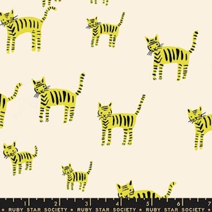May include: Cream fabric featuring a repeating pattern of yellow cartoon tigers with black stripes. The tigers are in different poses. The text "RUBY STAR SOCIETY" is printed along the bottom edge of the fabric.