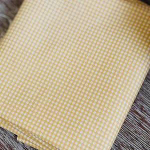 May include: A folded piece of yellow fabric with a white gingham pattern.