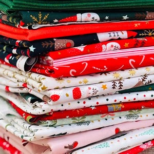 Pode incluir: Uma pilha de tecidos dobrados com temas natalinos em várias cores e padrões. Os desenhos incluem bengalas doces, flocos de neve, árvores de Natal e Papai Noel. As cores incluem vermelho, verde, branco e azul claro. Ideal para projetos de costura de férias.