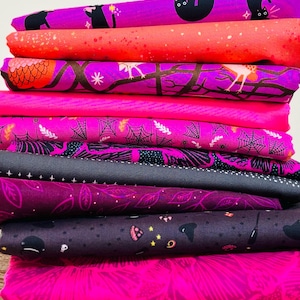 Pode incluir: Uma pilha de tecidos dobrados com vários padrões, incluindo gatos pretos, teias de aranha, folhas de outono e motivos de bruxas em tons vibrantes de magenta, rosa choque, laranja, preto e roxo escuro com detalhes de estrelas.