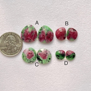 Könnte beinhalten: Vier Paare von Rubin-Edelsteinen mit grünen und roten Mustern. Die Edelsteine haben verschiedene Formen, darunter tropfenförmig und rund. Eine US-Vierteldollarmünze dient zum Größenvergleich.