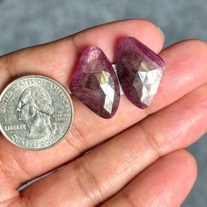 Op de afbeelding: Twee roze gefacetteerde edelsteen cabochons, elk ongeveer zo groot als een Amerikaanse kwart.