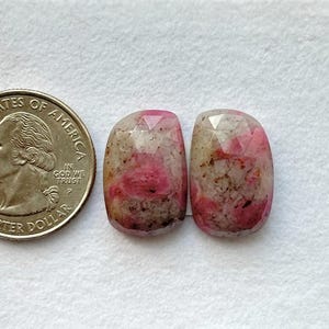 Peut inclure: Deux pierres précieuses facettées, roses et beiges, sont présentées à côté d'une pièce de 25 cents américaine. Les pierres ont une forme rectangulaire arrondie et des teintes roses et beiges. La pièce donne une indication de la taille.