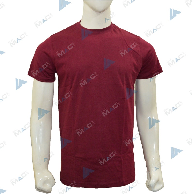 May include: A plain maroon crew neck t-shirt. The short-sleeved shirt is displayed on a white mannequin. The text "the MAC" is printed repeatedly on the shirt. The shirt is made of a soft, comfortable material.