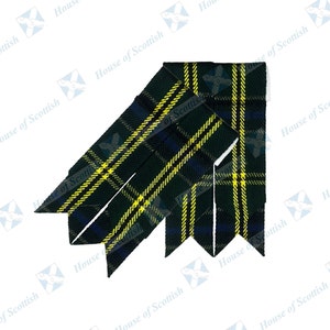 Op de afbeelding: Een groene, gele en blauwe tartan kiltpin met een puntige punt. De pin is dubbelgevouwen en heeft een witte achterkant.