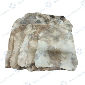 May include: A stack of five natural-colored leather hides. The hides are irregularly shaped and have a mottled, textured surface.