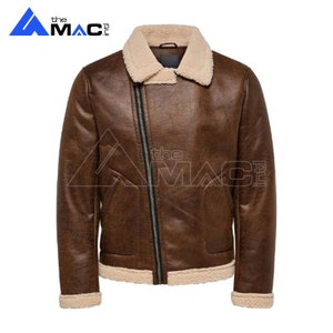 May include: Brown leather jacket with a cream-colored shearling collar and lining. The jacket features an asymmetrical zipper closure and a classic aviator style. The brand logo "the MAC" is visible in the upper left corner.