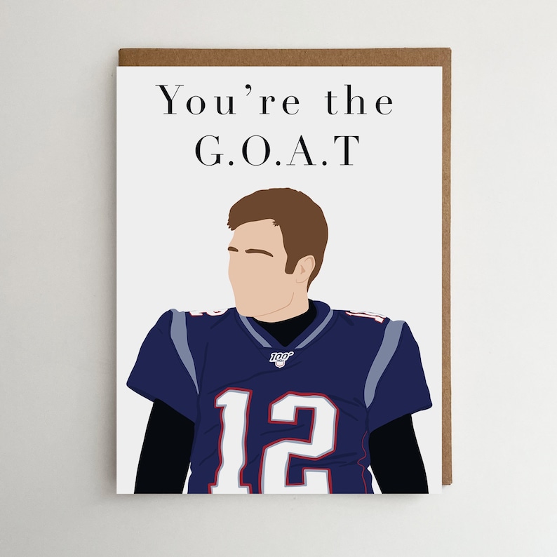 May include: A greeting card with a cartoon illustration of a football player wearing a blue and white jersey with the number 12. The text on the card reads "You're the G.O.A.T."