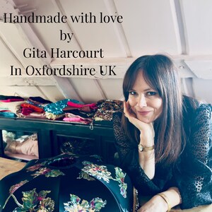 May include: A woman smiles next to a black lampshade with a floral design and gold fringe. The image includes the text "Handmade with love by Gita Harcourt In Oxfordshire UK."
