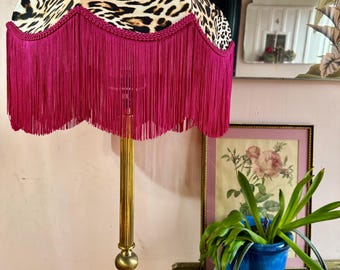 May include: A gold floor lamp with a leopard print lampshade trimmed with a pink fringe.