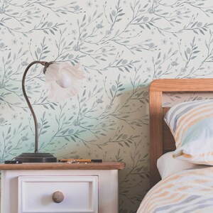 May include: A bedroom with a white and gray floral wallpaper, a wooden bed frame with a striped comforter and pillows, and a white nightstand with a lamp.