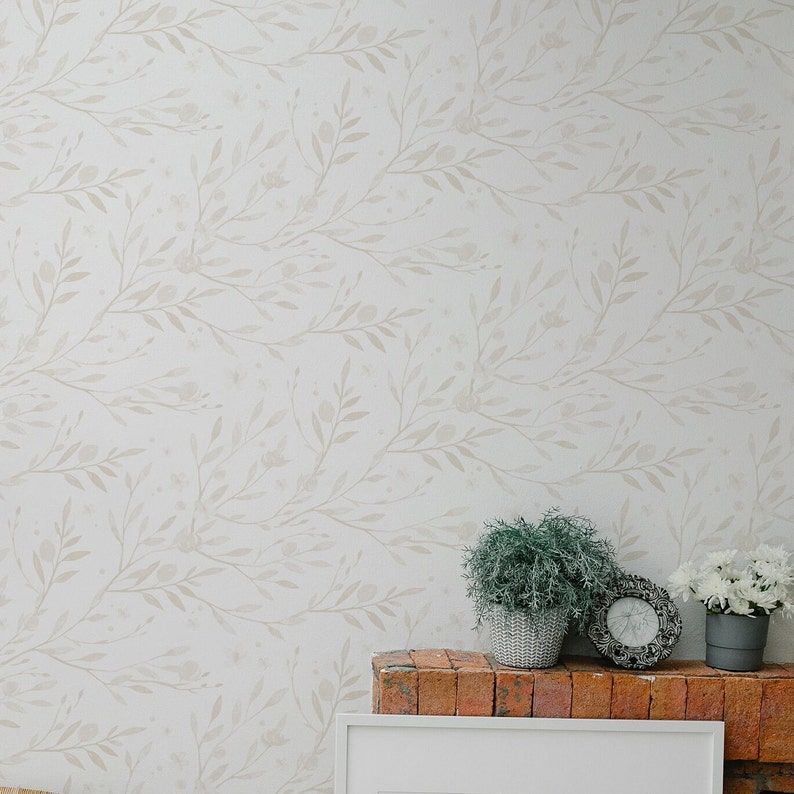 May include: A white wall with a beige floral pattern wallpaper. A brick fireplace mantel with a white frame and two potted plants.