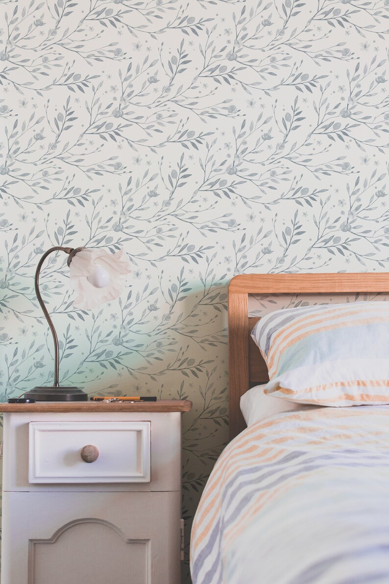 May include: A bedroom with a white and gray floral wallpaper, a wooden bed frame with a striped comforter and pillows, and a white nightstand with a lamp.