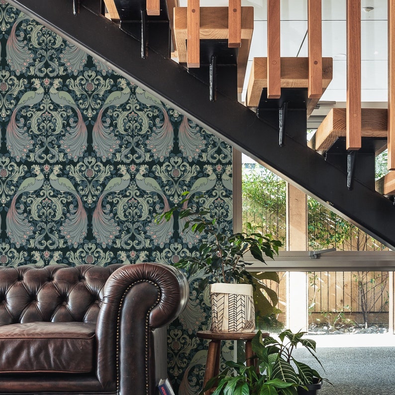 May include: A dark blue and green wallpaper with a repeating pattern of peacocks and floral designs. The wallpaper is on a wall in a home with a leather couch and a wooden staircase.