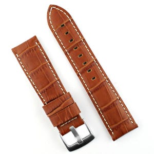 May include: Two-piece brown watch strap with a crocodile pattern. The leather strap features white stitching along the edges and a silver-colored buckle. The watch band is designed to fit a standard watch.