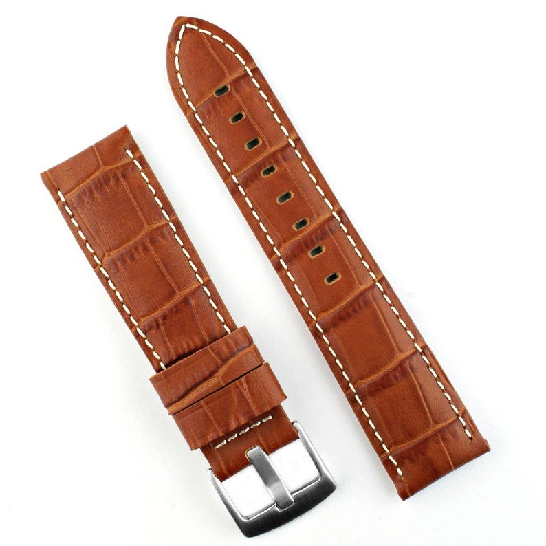 May include: Two-piece brown watch strap with a crocodile pattern. The leather strap features white stitching along the edges and a silver-colored buckle. The watch band is designed to fit a standard watch.