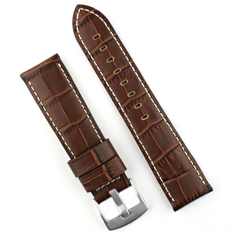 May include: Two-piece brown leather watch strap with a crocodile pattern. The strap features white stitching and a silver-colored buckle. The watch band is designed to be attached to a watch face.