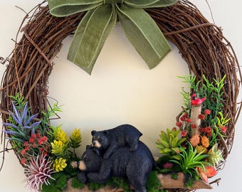 momma black bear and cub napping on a log in the woods surrounded by succulents