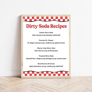 May include: A framed print featuring "Dirty Soda Recipes" in red text. The recipes include Classic Dirty Soda, Coconut Dr. Pepper, Cherry Lime Dirty Coke, Tropical Dirty Soda, and Strawberries & Cream. The frame has a red and white checkered border.