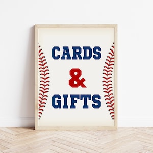 Può includere: Un cartello bianco con un bordo di cuciture da baseball. Il cartello dice "CARDS & GIFTS" in lettere blu e rosse.