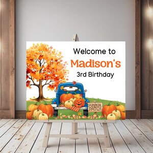 Könnte beinhalten: Ein Willkommenszeichen für eine 3. Geburtstagsparty mit einem blauen LKW, der mit Kürbissen gefüllt ist, und einem Herbstbaum im Hintergrund. Das Schild lautet "Welcome to Madison's 3rd Birthday".