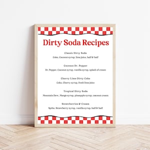 May include: A framed print featuring "Dirty Soda Recipes" in red text. The recipes include Classic Dirty Soda, Coconut Dr. Pepper, Cherry Lime Dirty Coke, Tropical Dirty Soda, and Strawberries & Cream. The frame has a red and white checkered border.