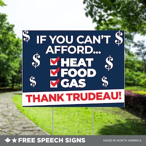 May include: A blue and white yard sign with the text "IF YOU CAN'T AFFORD... HEAT, FOOD, GAS. THANK TRUDEAU!" and dollar signs. The sign is on metal stakes, set in a grassy area with trees in the background. The bottom of the sign reads "FREE SPEECH SIGNS".