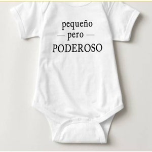 May include: White baby onesie with black text that reads "pequeño pero PODEROSO".