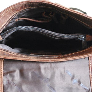 May include: The inside of a brown leather crossbody bag with a zippered pocket and a brown fabric lining.