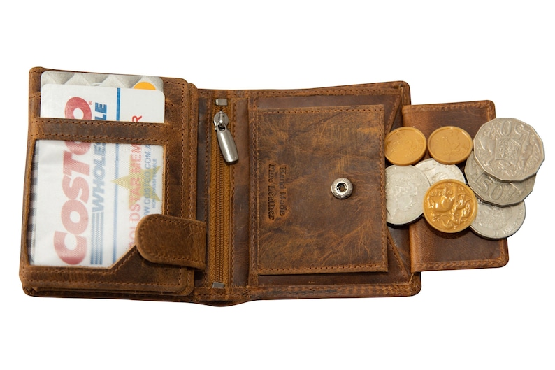 May include: A brown leather wallet with a zipped pocket and a coin pocket. The wallet is open and contains a Costco membership card. The coin pocket is filled with coins.