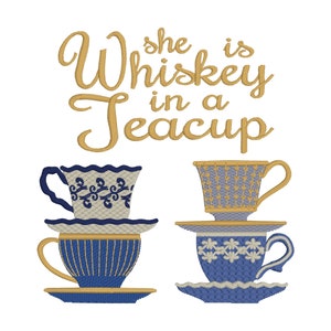May include: Embroidered design with the text "She is Whiskey in a Teacup" in gold script above four stacked teacups. The teacups are blue, white, and gold, with detailed patterns.