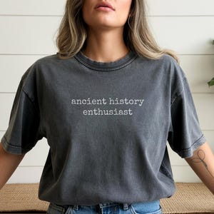 Pu&ograve; includere: T-shirt grigio scuro con la scritta bianca "ancient history enthusiast". La maglietta ha maniche corte e girocollo. La maglietta &egrave; realizzata in un materiale morbido e confortevole.