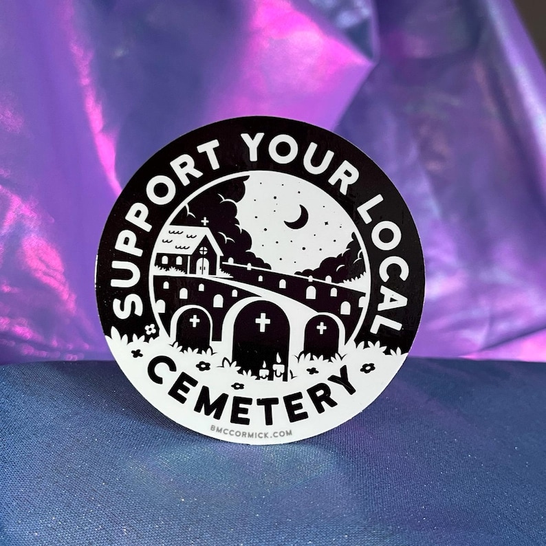 May include: Black and white sticker with the text "Support Your Local Cemetery" in a circle around a spooky illustration of a graveyard at night with a church, a crescent moon, and tombstones.