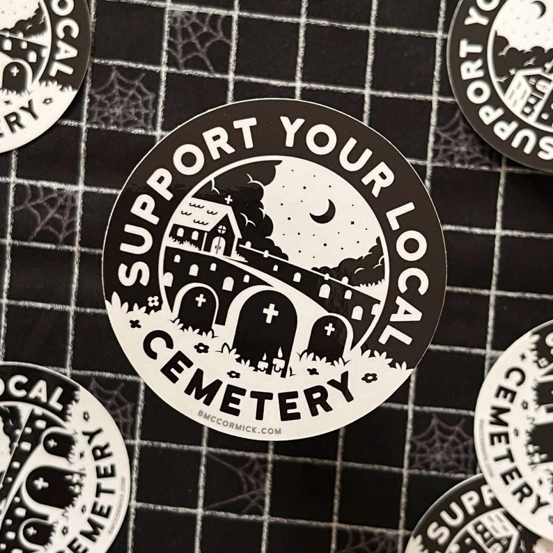 May include: Black and white sticker with a spooky illustration of a graveyard at night. The sticker says "Support Your Local Cemetery" with a small church, a bridge, and tombstones.