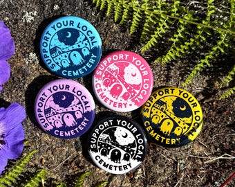 May include: Five circular badges with the text "Support Your Local Cemetery." Each badge features a cemetery design with a moon and bridge. The colours are blue, pink, purple, black, and yellow.