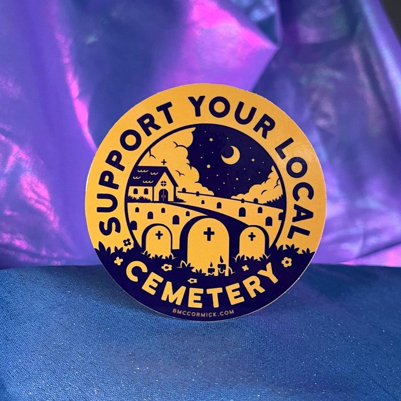 May include: A yellow circle sticker with the text "Support Your Local Cemetery" in a dark blue font. The sticker features a black silhouette of a small church, a crescent moon, and a graveyard with tombstones.