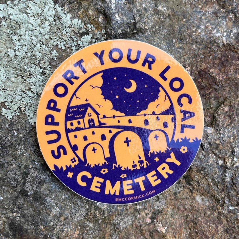 May include: A round sticker with an orange background and purple text. The text says "Support Your Local Cemetery" with a small church, a crescent moon, and stars in the background. The sticker also has a website address at the bottom: "bmccormick.com".